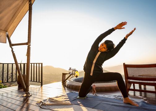 woman practising yoga on wooden deck above Chiang Rai