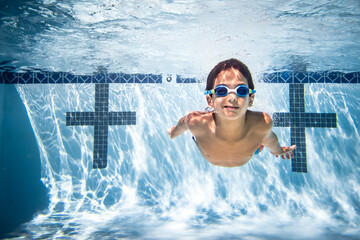 Underwater photograph of boy swimming in goggles.