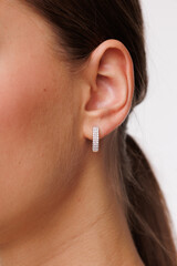 Beautiful young girl with fresh  healthy skin. Woman advertise ear-rings. White background. Earrings closeup. Blond european woman with long hair with big lips, pretty smile. Cosmetology,  scincare