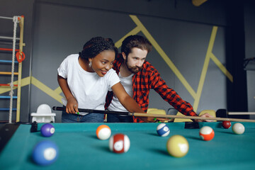 International couple playing a billiard in a club