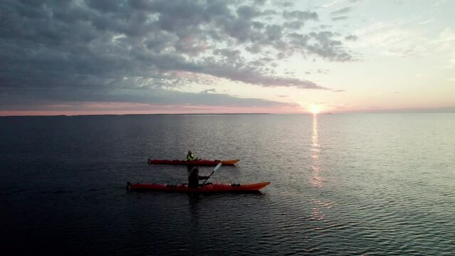 Aerial Shot of a Young Couple Paddling in Red Sea Kayak on the open Sea in Finland, Vaasa, Archipelago, Beautiful Peaceful Summer Sunset Atmosphere, Camera Paning