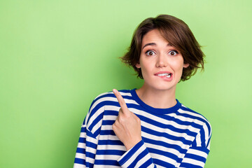 Photo of impressed woman bob hairstyle sailor shirt biting lips indicating at hot sale empty space isolated on green color background