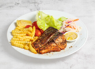 grilled salmon with lemon, salad, tomato and dip served in dish isolated on banana leaf top view of singapore food