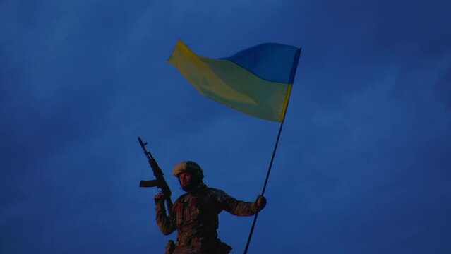 An evening photo of Ukrainian defender holding a national flag
