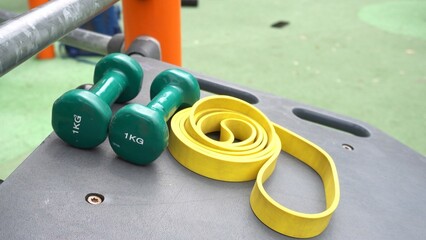 1 kg weights and elastic rope to do physical exercises in the outdoor gym and train the body - sports equipment area in a park and start of the summer diet - sport activities during holidays 