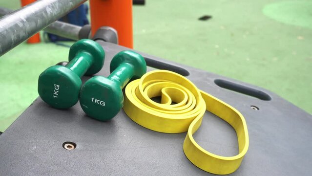 1 kg weights and elastic rope to do physical exercises in the outdoor gym and train the body - sports equipment area in a park and start of the summer diet - sport activities during holidays 