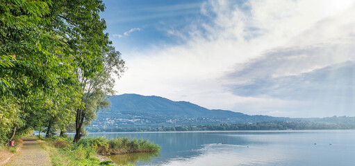 Lake Varese in summer, Italy. Cycle pedestrian track that runs along all the lake near Biandronno village. In the background the mountain called Campo dei Fiori is visible