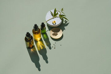 Various glass bottles with oil and tincture of CBD and a branch in hemp