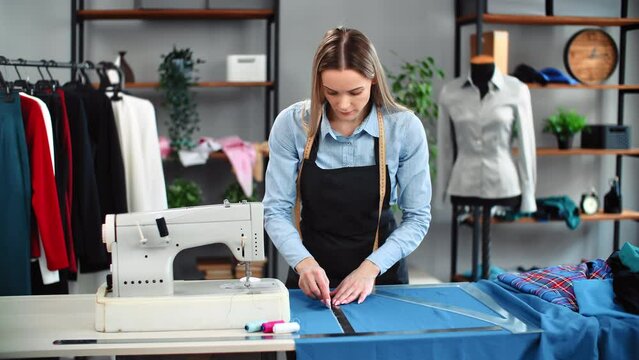 Skilled woman seamstress drawing pattern marking fabric for clothes sewing use chalk and ruler