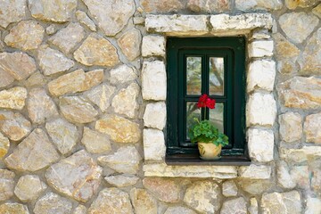 Fototapeta na wymiar Window in old stone house with flower. High quality photo