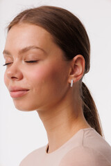 Beautiful young girl with fresh  healthy skin. Woman advertise ear-rings. White background. Earrings closeup. Blond european woman with long hair with big lips, pretty smile. Cosmetology,  scincare