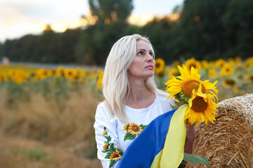 Love Ukraine concept.Beautiful girl in an embroidered shirt with ukrainian flag and sunflowers....