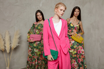 Three fashion models. Asians in identical looks, green dress with floral pattern, handbag, clutch....