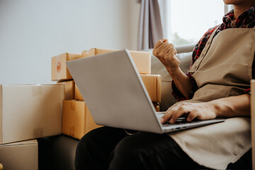 Startup small entrepreneur young asian man working with boxes and laptop for packaging order from online shopping at home for online business and online shopping.