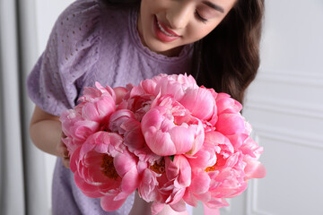 Young woman near bouquet of pink peonies indoors, closeup