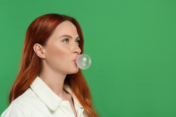 Beautiful woman blowing bubble gum on green background. Space for text