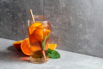 Cocktail with mint, and orange on a grey background.