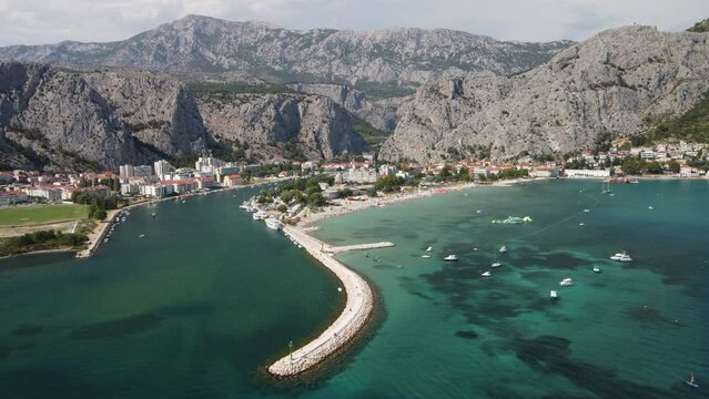 Panoramic aerial of Coastal Omis Town in Croatia with its rugged mountains background, sandy Beachfront and Cetina River mouth meeting adriatic Sea