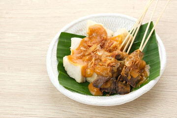Sate Padang, beef satay from West Sumatra, Indonesia, served with spicy curry sauce and ketupat
