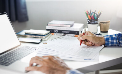 Asian businessman working with laptop computer to reviewing document reports at office workplace with. legal expert, professional lawyer reading and checking financial documents or insurance contract