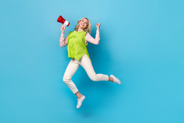 Full length portrait of excited cheerful person jumping hold loudspeaker empty space isolated on blue color background