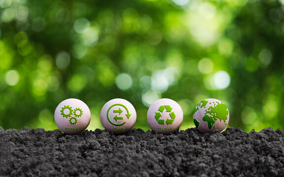 Environmental concept. Word reduce, reuse, recycle on small round wooden blocks placed on soil with natural green background.