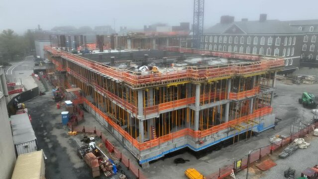 Large building under construction. Aerial establishing shot of big construction project on foggy day.