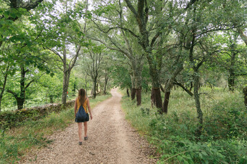 Anonymous female walking on path in woodland