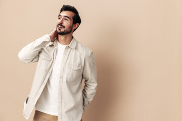 Fototapeta premium Portrait of a stylish man smile with teeth happiness opened his mouth in surprise on a beige background in a white t-shirt looks at the camera, fashionable clothing style, copy space, space for text