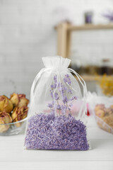 Scented sachet with dried lavender flowers on white table