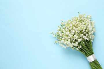 Beautiful lily of the valley bouquet on light blue background, top view. Space for text