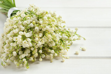 Beautiful lily of the valley bouquet on white wooden table, closeup. Space for text