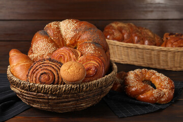 Wicker baskets and different tasty freshly baked pastries on wooden table