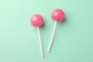 Tasty lollipops on turquoise background, flat lay