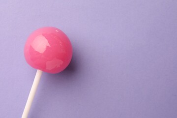 Tasty lollipop on violet background, top view. Space for text