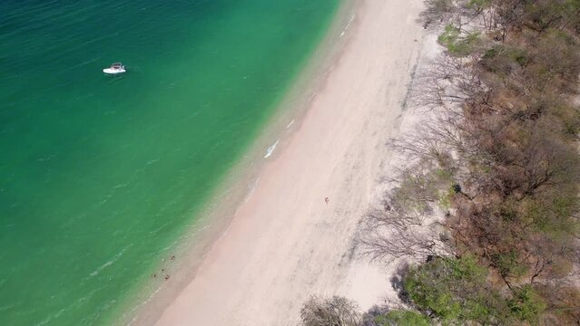 Aerial drone panning shot over a tranquil clear ocean next to Playa Conchal.