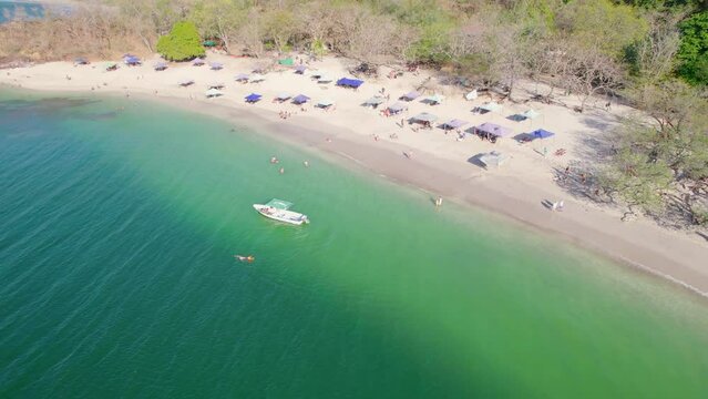 Backwards drone dolley shot of people enjoying the summer at a beach in Costa Rica