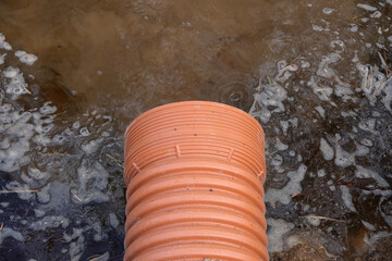 Drainage pipe with water stream flowing. Storm water management in public space, plastic pipe,...
