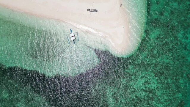Top down perspective pan across patawan island, banca boats beached and coastline