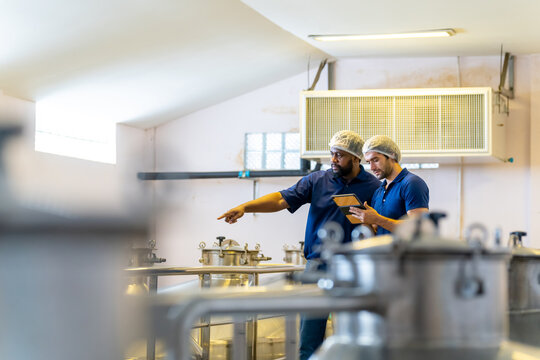 Winemaker staff worker inspecting wine sediment in the bottle in modern wine factory. Winery manufacturing quality control. Alcohol and wine winemaking process concept.