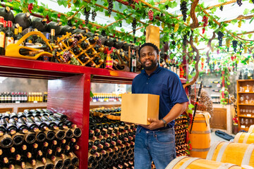 African man liquor shop worker working and counting a bottle of wine, champagne or beer on shelf in...