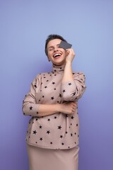 portrait of a young looking woman with gray streaked short hair holding a bank card