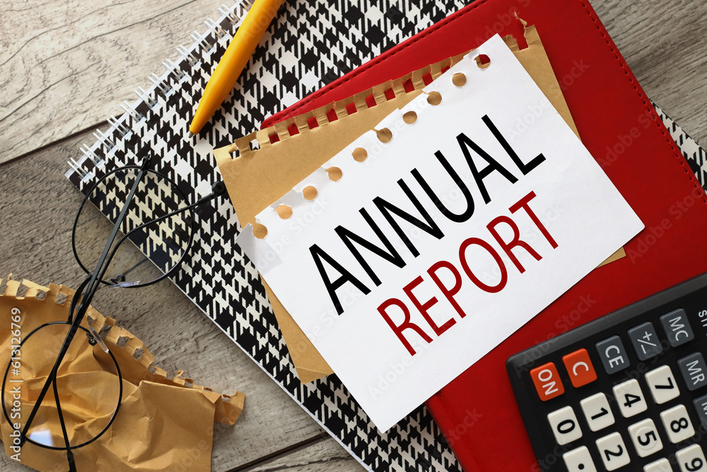Fototapete Annual Report wooden background with sheets of paper on a red notepad. word on page