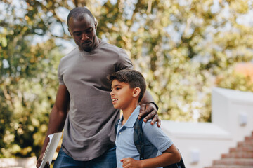 Male teacher walking outdoors with a young student