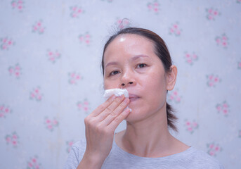 Middle-aged Asian women aged around 40-50 years old with aging skin. Soak a cotton ball in facial...
