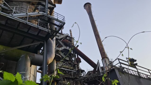 historic green industrial building surrounded by nature with steel stairs and pipes and schronsteienen landschaftspark, duisburg, germany
