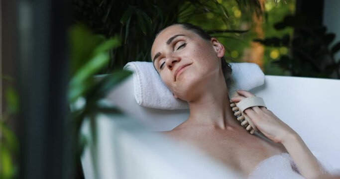 woman enjoying wellness spa bath with wooden massage brush. body care
