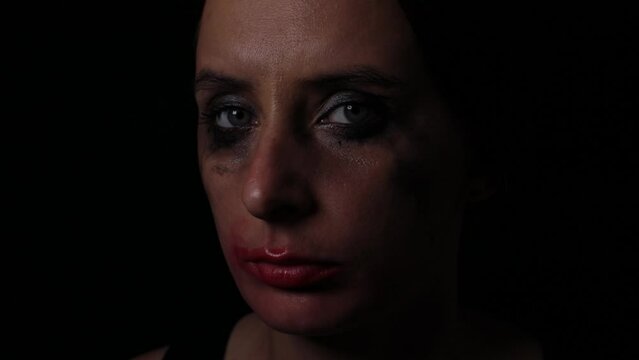 Upset young tearful woman with leaky mascara makeup on black background