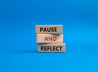 Pause and Reflect symbol. Concept words Pause and Reflect on wooden blocks. Beautiful blue...