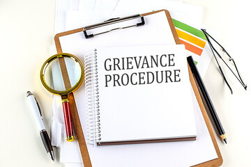 GRIEVANCE PROCEDURE text on notebook with clipboard on white background